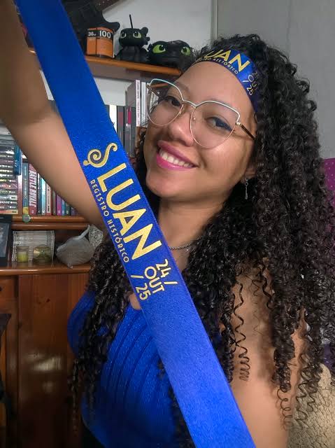Bandana com letras douradas, usada na cabeça e segurada na mão